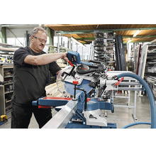 Un homme utilise une scie à onglet Bosch dans un atelier.