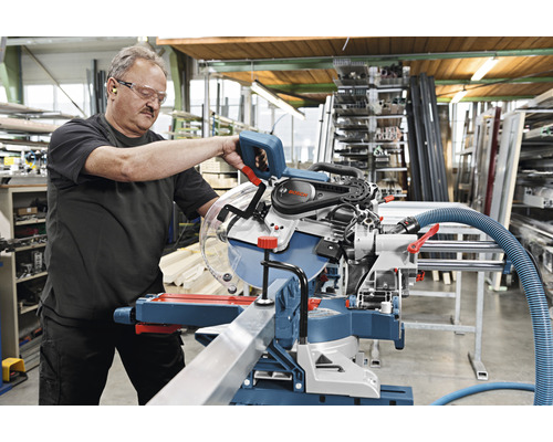 Un homme utilise une scie à onglet Bosch dans un atelier.