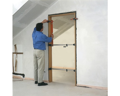 Un homme installe une porte à l''aide d''un écarteur de porte dans un bâtiment en construction