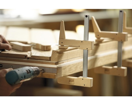 Handwerker montiert Holztür mit Schraubzwingen und Akkuschrauber