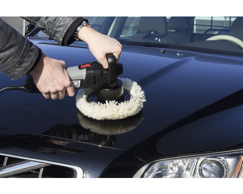 Ein Mann poliert mit einer Poliermaschine die Motorhaube eines Autos.