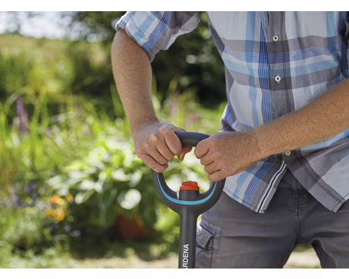 Eine Person hält einen Spaten der Marke Gardena im Garten.