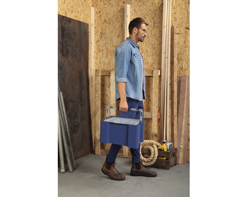 Homme portant une boîte à outils dans un atelier