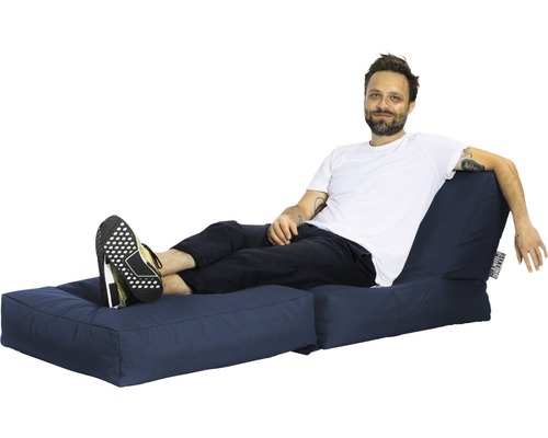 Mann entspannt sich auf einem blauen Loungesofa.