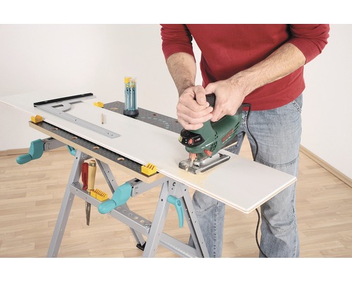 Une personne coupe une pièce à travailler avec une scie sauteuse sur un établi.