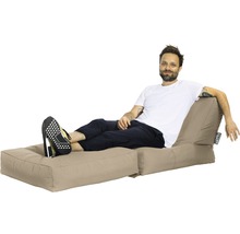 Un homme se détend sur un pouf beige avec repose-pieds