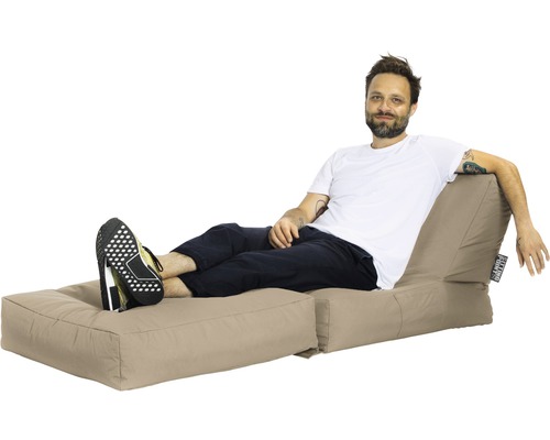 Un homme se détend sur un pouf beige avec repose-pieds