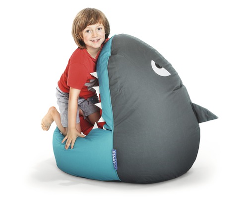 Garçon grimpant sur un pouf en forme de requin.