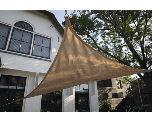 Dreieckiges Sonnensegel vor einem Gebäude mit Fenstern und einem Baum.