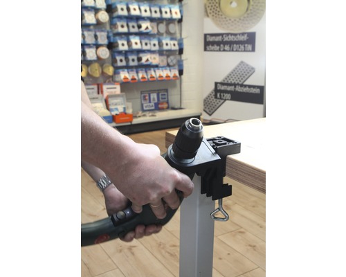 Une perceuse avec support de perçage est fixée à un plateau de table.