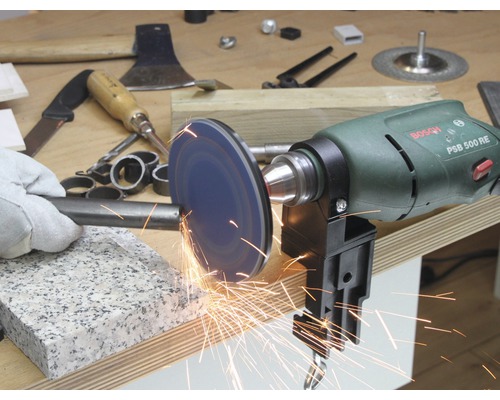 Une perceuse avec disque à poncer travaille une pièce métallique, des étincelles volent.