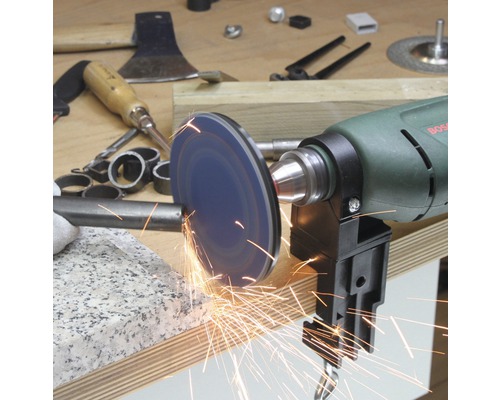 Une perceuse avec une meuleuse rectifie une pièce métallique, des étincelles jaillissent