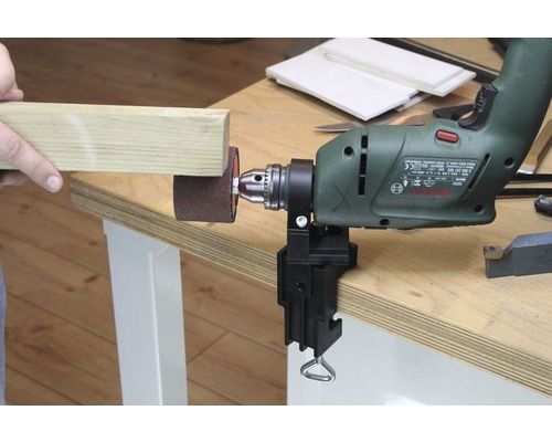 Perceuse avec accessoire de ponçage et pièce sur un établi