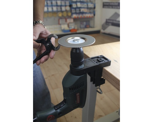 Personne affûtant une pince avec une meule sur une perceuse