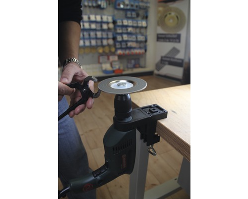 Une perceuse est fixée à un établi et aiguise un outil.