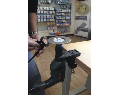 Une personne aiguise une pince avec un accessoire de meulage sur une perceuse.