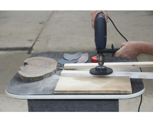 "Eine Person schleift ein Holzbrett mit einer elektrischen Schleifmaschine