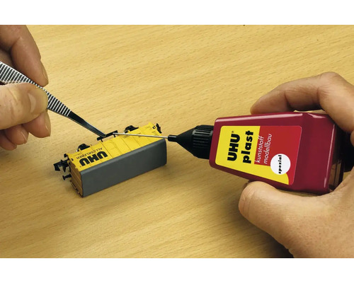 Uhu Plast Spezial Klebstoff wird mit einer Pinzette auf ein Modellteil aufgetragen