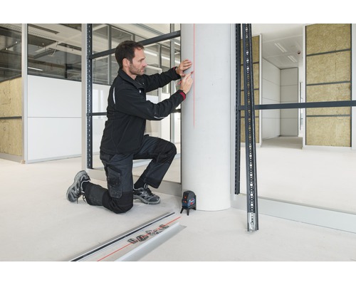 Handwerker mit Kreuzlinienlaser bei der Montage einer Metallunterkonstruktion im Innenausbau.