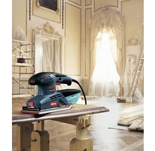 Logo Bosch. Ponceuse vibrante sur une table en bois dans une pièce rénovée.