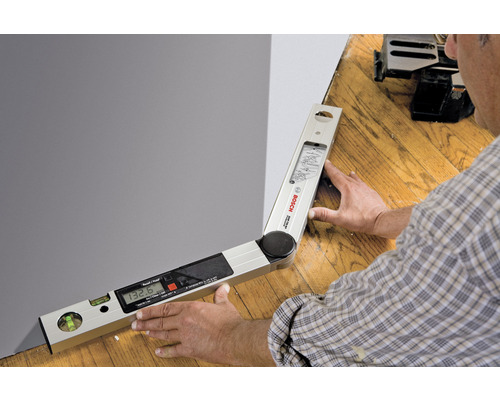 Un rapporteur d'angle numérique en cours d'utilisation, pour mesurer un angle sur un mur.