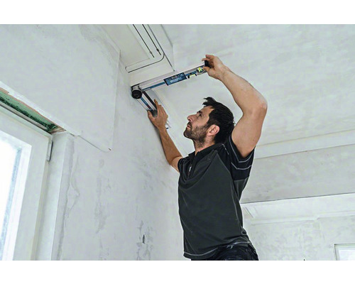 Un homme utilise un niveau à bulle pour des travaux de rénovation à l'intérieur.