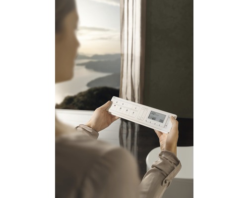 Femme tenant un système domotique dans une salle de bain.