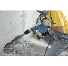 Ein Bauarbeiter verwendet einen Bohrhammer zum Bohren eines Lochs in eine Betonwand.