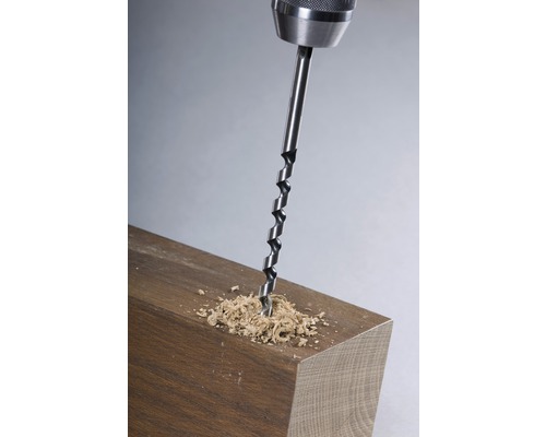 Holzbohrer im Einsatz an einem Holzstück mit Bohrspänen