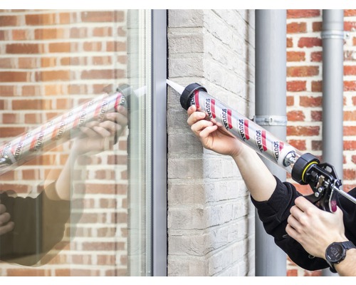 Person dichtet Fenster mit Dichtstoff und Kartuschenpistole ab