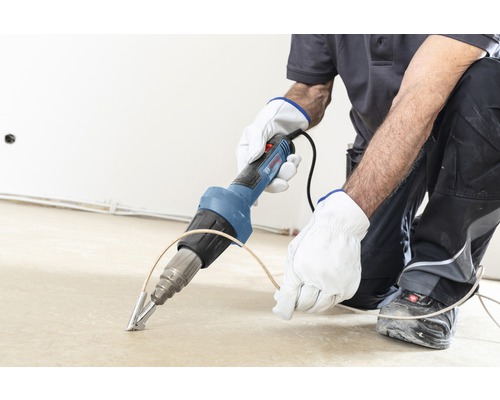 Artisan travaillant le sol avec un pistolet à air chaud de marque Bosch