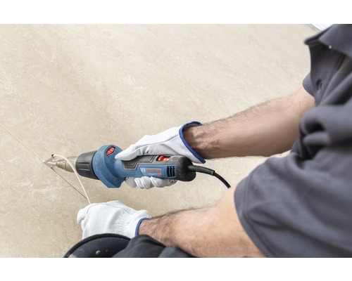 Artisan utilisant un pistolet thermique Bosch pour des travaux d''installation