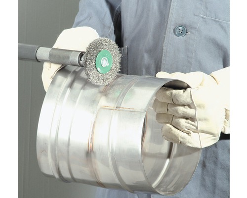 Eine Person reinigt ein Metallrohr mit einer Drahtbürste