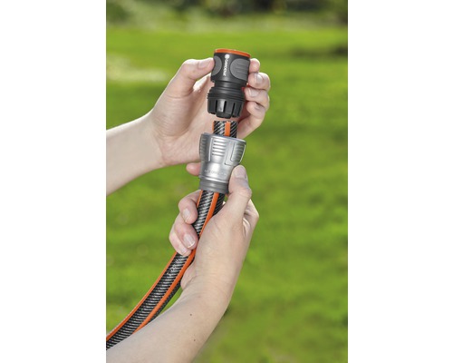 Zwei Hände verbinden einen Gartenschlauch mit einem Kupplungsstück.