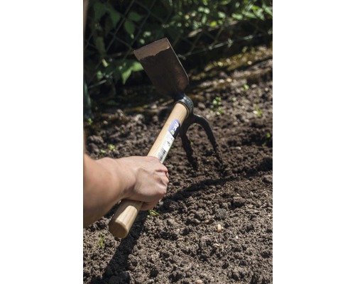 Hand hält eine Doppelfunktionshacke im Gartenboden