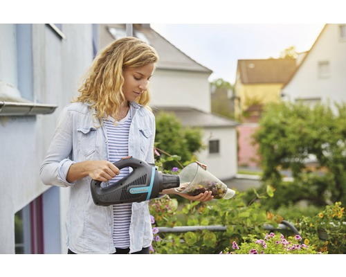 Frau leert einen Gardena Akku-Handsauger über Blumen aus