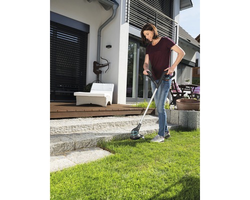Femme utilisant un coupe-bordures dans le jardin.