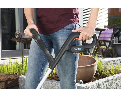 Une personne utilise un coupe-bordures à batterie dans le jardin.