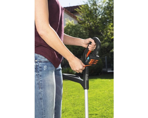 Une personne utilise un coupe-bordures dans le jardin.