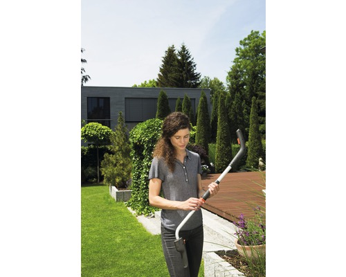 Une femme tient des cisailles à gazon sans fil dans le jardin.