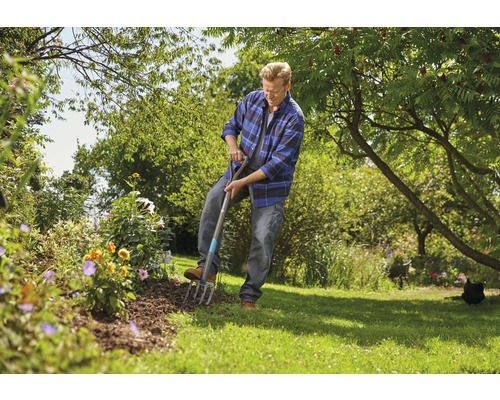 Ein Mann benutzt eine Grabgabel im Garten, um ein Blumenbeet zu bearbeiten.
