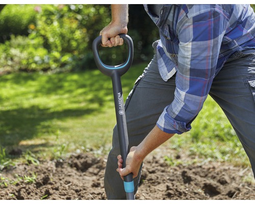 Une personne creuse dans le jardin avec une bêche.