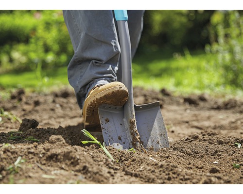 Personne enfonce une bêche dans la terre du jardin