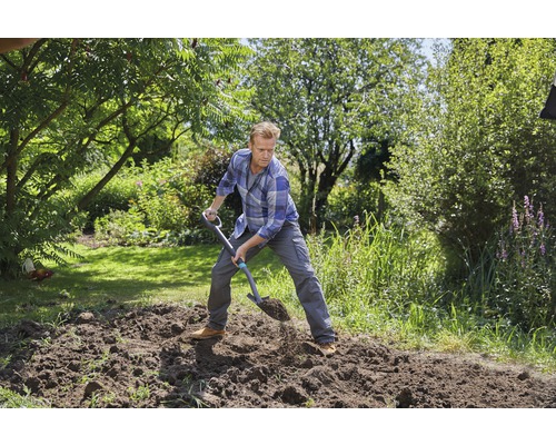 Un homme bêche la terre dans le jardin avec une bêche