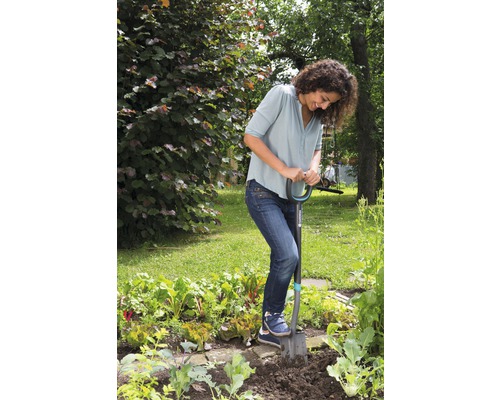 Une femme utilise une bêche dans le potager.
