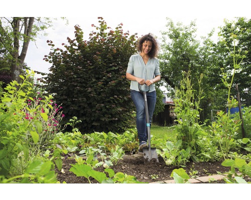 Femme utilisant une bêche dans un potager.