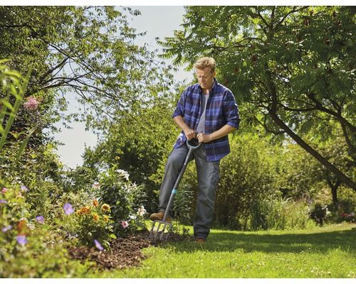 Homme travaillant avec une fourche bêche dans le jardin.