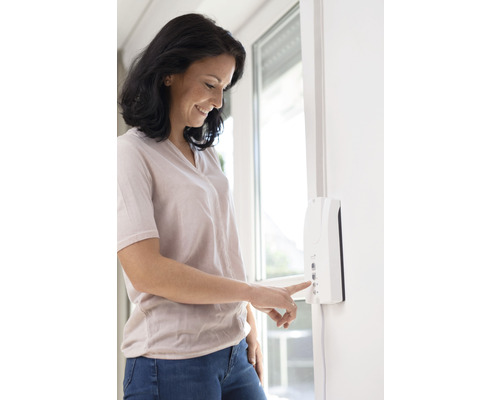 Frau bedient Rollladensteuerung an der Wand