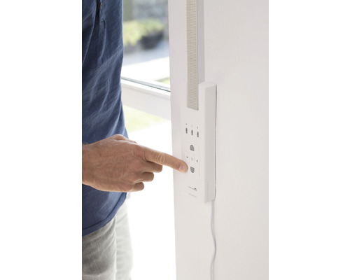 Une personne actionne une commande de volet roulant sur le mur