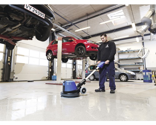 "Mann reinigt Werkstattboden mit Reinigungsmaschine